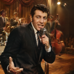 Freddy Cannon performing with a microphone on a vintage 1950s rock-and-roll stage.