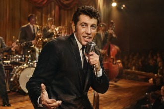 Freddy Cannon performing with a microphone on a vintage 1950s rock-and-roll stage.